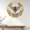 Custom honeybee metal sign displayed on a light wood-paneled wall above a console table