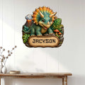 Triceratops dinosaur wall sign displayed on a light wood-paneled wall in a home interior