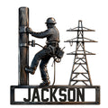 Lineman metal sign featuring a utility worker climbing a power pole beside an electrical transmission tower
