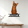Abyssinian cat metal wall sign displayed on a light wood-paneled wall above a console table