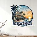 Beach house wall sign displayed on a white paneled wall, featuring a tropical home, palm trees, and ocean sunset