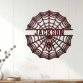 Spider web metal wall sign displayed on a light paneled wall above a console table