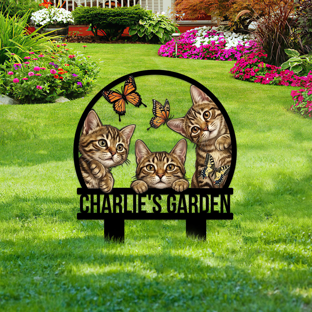 Tabby cat metal garden sign shown among colorful flower beds and green lawn landscaping