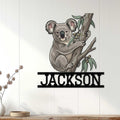 Koala metal wall sign displayed on a light wood-paneled wall in a welcoming home setting