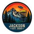 Custom disc golf metal sign featuring a mountain course, evergreen forest, sunset, and flying disc