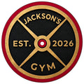 Close-up of a custom weightlifting metal sign featuring a gold barbell plate design on a textured black background
