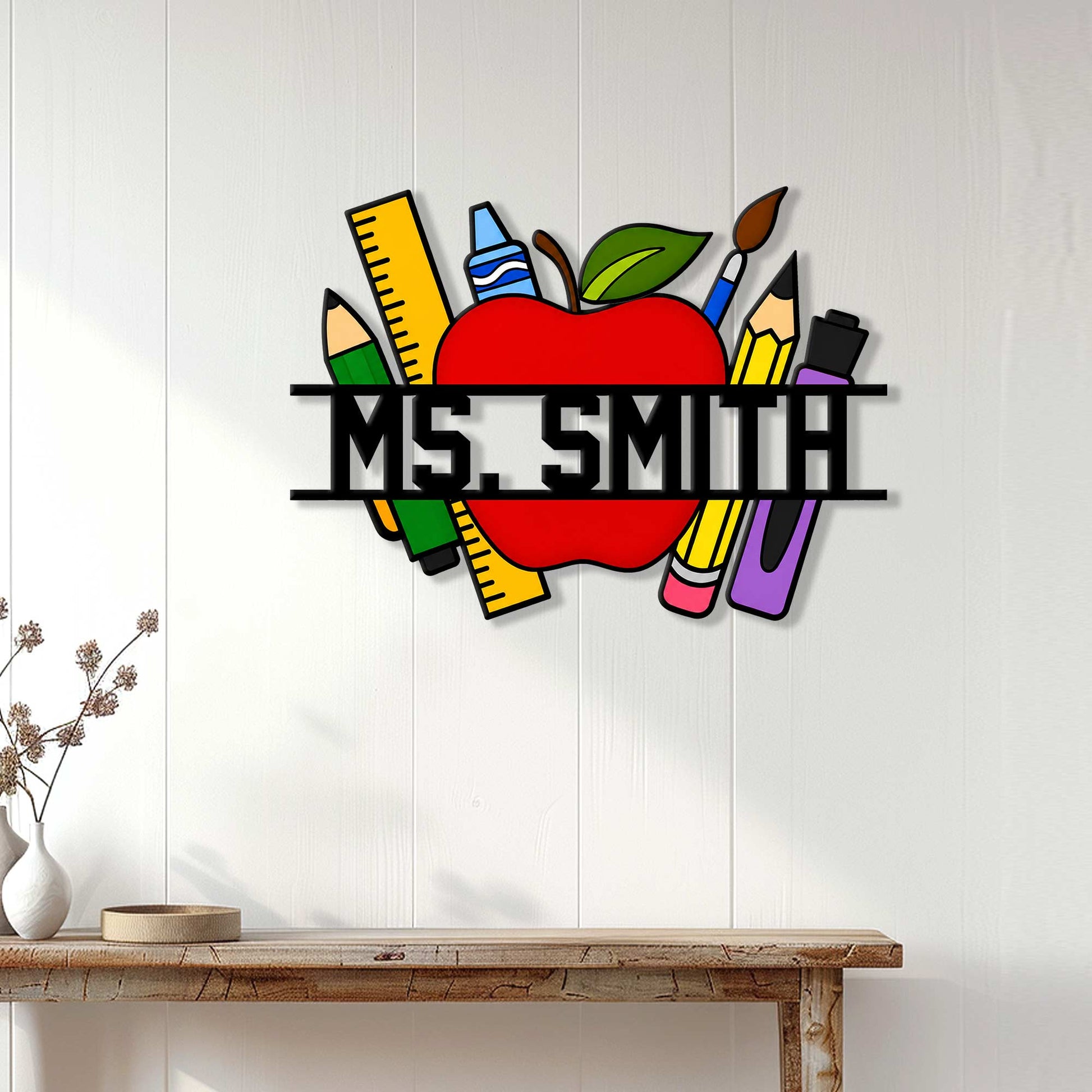Teacher apple metal sign displayed on a white paneled wall above a wood console table