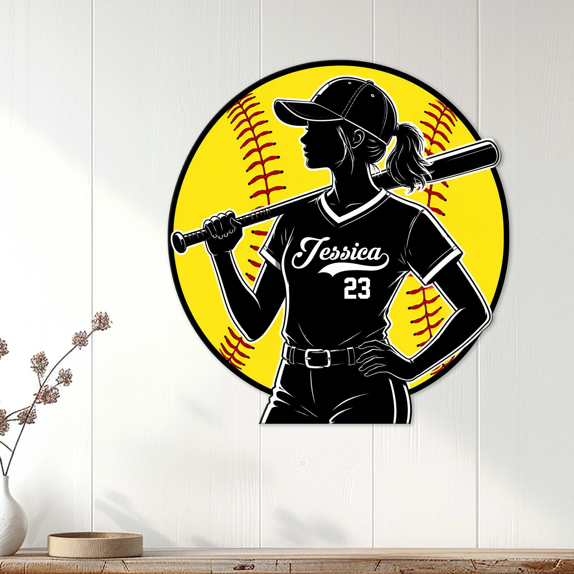 Softball wall decor displayed on a white paneled wall, featuring a female batter silhouette and vivid yellow baseball