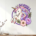 Whimsical unicorn metal wall sign displayed on a light wood-paneled wall in a bright room