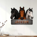 Three-horse metal wall sign displayed on a light wood-paneled wall in a home decor setting