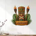 Tropical tiki bar wall decor displayed on a light wood wall above a console, featuring a bold tiki mask and torches