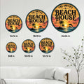 Beach house metal sign shown in multiple size options above a coastal-style sofa