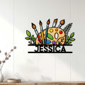 Colorful artist metal sign displayed on a light wood-paneled wall in a bright creative living space