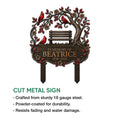 Cut metal cardinal memorial sign featuring a tree, bench, flowers, and three red birds