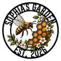Round bee garden metal sign featuring a honeybee, honeycomb, leafy branches, and white flowers