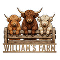 Three Highland cows leaning over a rustic fence on a custom metal farm sign