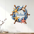 Nautical ship wheel wall sign displayed on a white paneled wall in a bright coastal home
