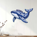 Ornate whale wall decor displayed on a light wood-paneled wall in a bright coastal-style room