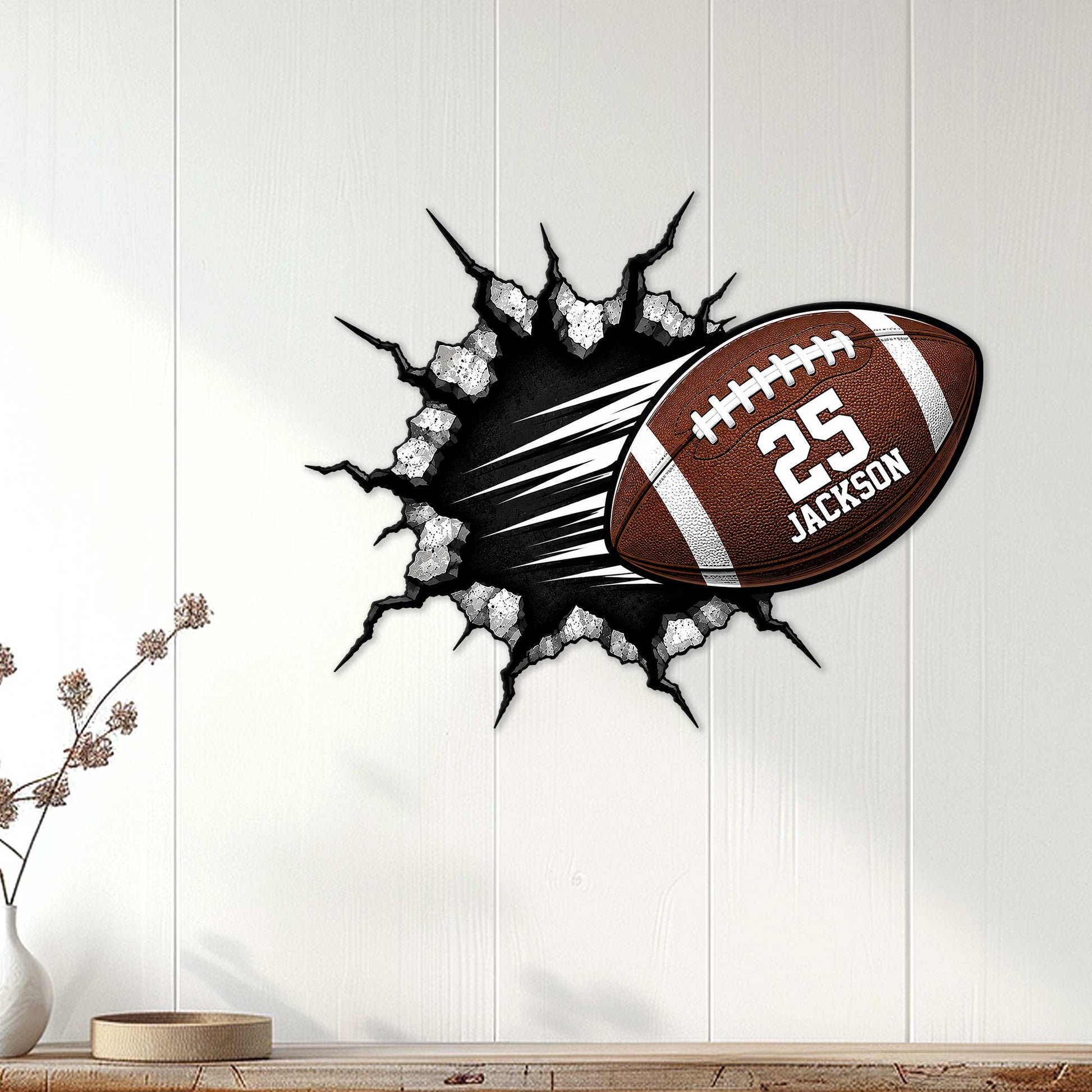 Football wall decor displayed on white wood paneling, featuring a ball bursting through a rugged cracked surface