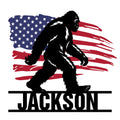 Bigfoot metal sign featuring a bold walking Sasquatch silhouette over a distressed American flag design