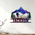 Custom hiking wall decor displayed on a light wood wall with colorful mountains, forest, trail, and hiker