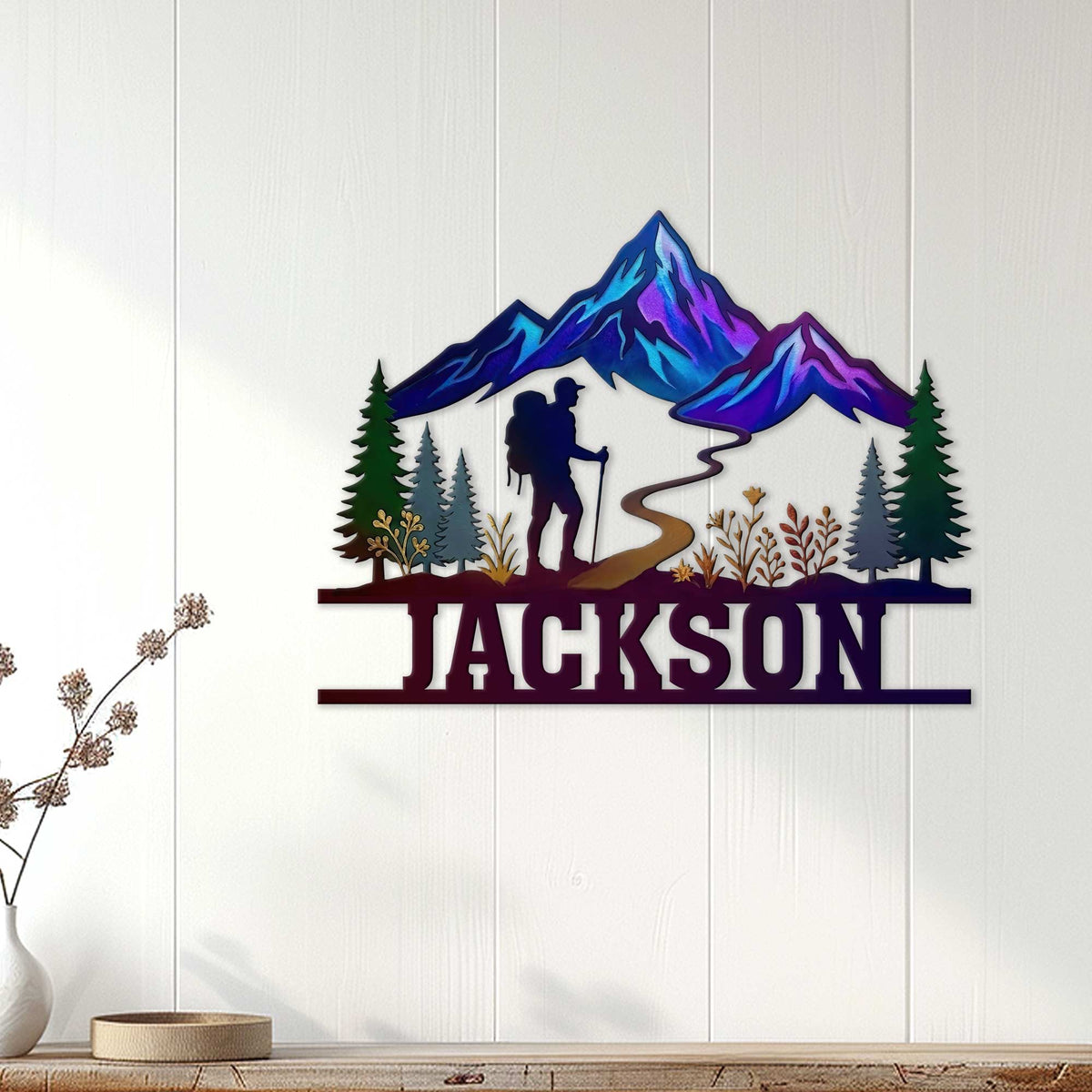 Custom hiking wall decor displayed on a light wood wall with colorful mountains, forest, trail, and hiker