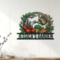 Garden metal sign displayed on a white wood wall, featuring colorful vegetables, leafy branches, bees, and a watering can