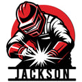 Bold red, black, and white welder metal sign featuring a protective helmet, welding sparks, and workwear
