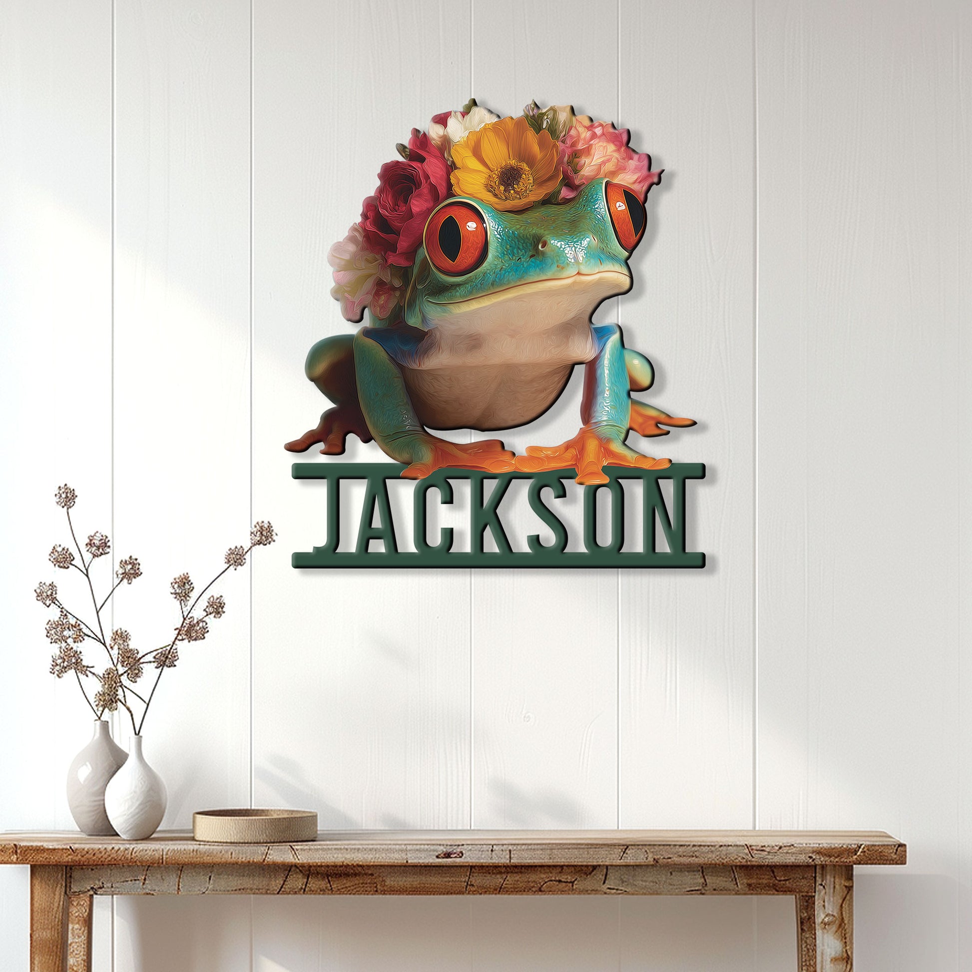Flower-crowned frog metal wall sign displayed on a bright paneled wall above a wooden console