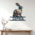 Decorative floral rabbit metal sign displayed on a white paneled wall above a console table