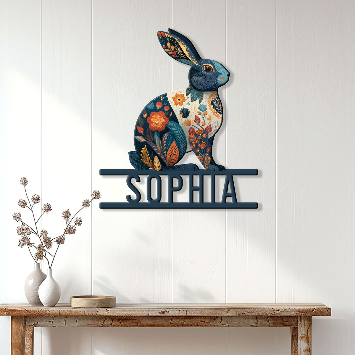 Decorative floral rabbit metal sign displayed on a white paneled wall above a console table