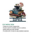 Cut metal book sign showcasing a floral teacup resting on stacked books with surrounding flowers