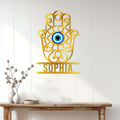 Gold Hamsa evil eye wall sign displayed on a bright paneled entryway above a console table