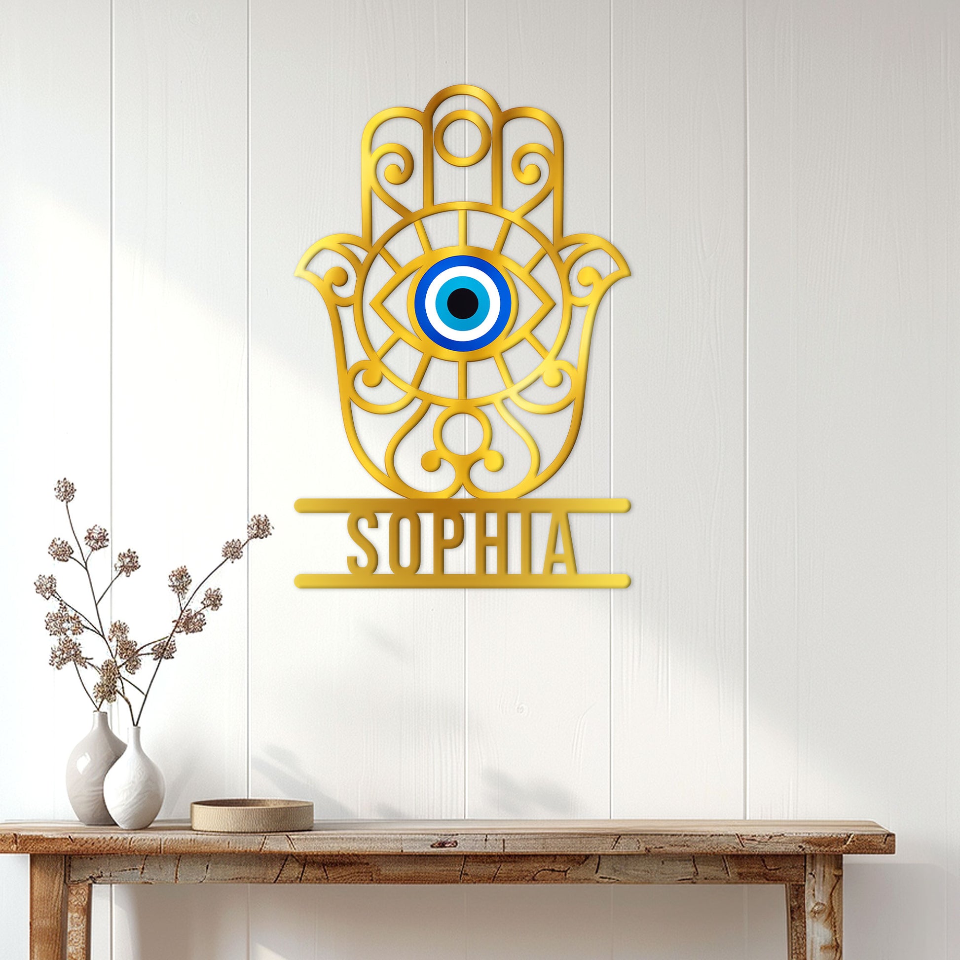 Gold Hamsa evil eye wall sign displayed on a bright paneled entryway above a console table