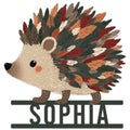 Colorful hedgehog metal sign featuring a woodland animal surrounded by layered autumn leaves