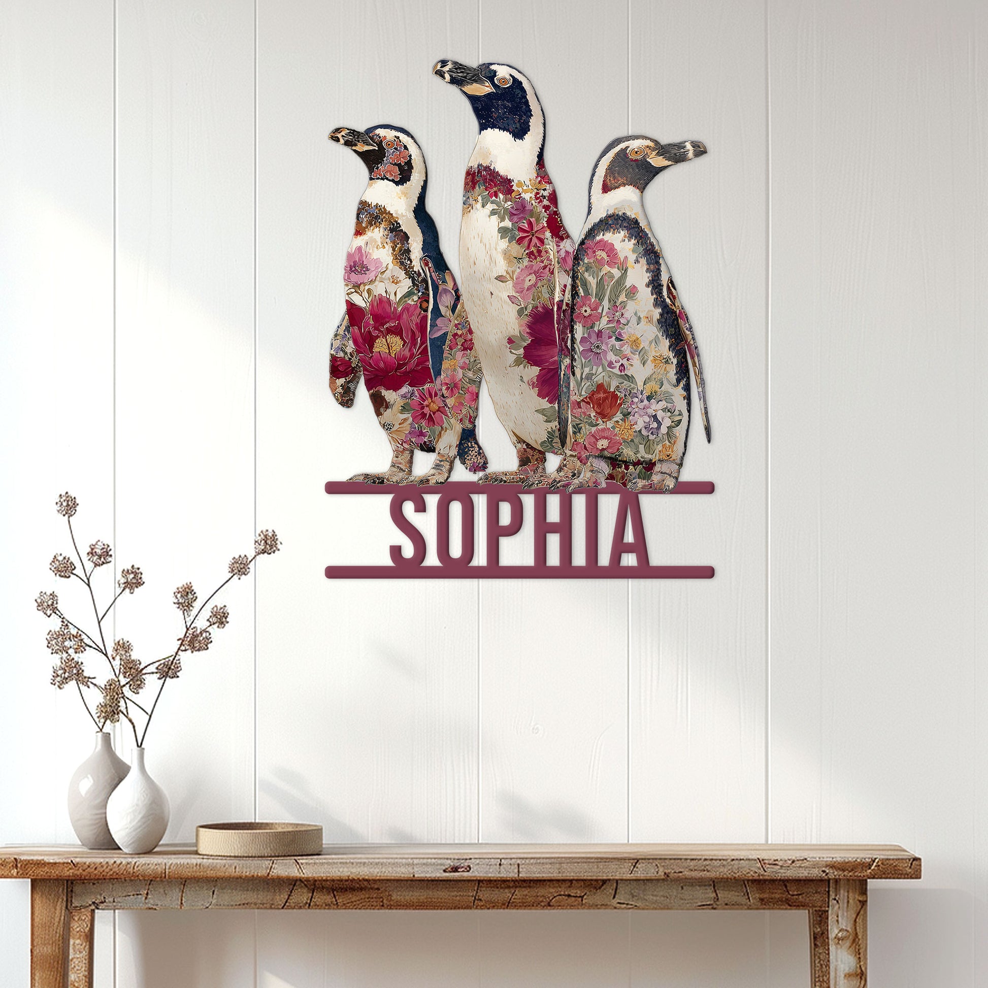 Floral penguin wall sign displayed on a light wood-paneled wall above a console table