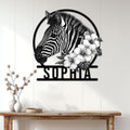 Zebra and hibiscus metal wall sign displayed on a light wood-paneled wall above a console table