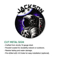 Round astronaut wall sign shown with a bold helmet illustration, Earth above, and colorful galaxy backdrop