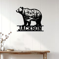 Bear silhouette metal wall sign displayed on a light wood-paneled wall above a rustic console table