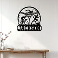 Triathlon wall decor displayed on a white paneled wall, featuring swim, bike, and run silhouettes