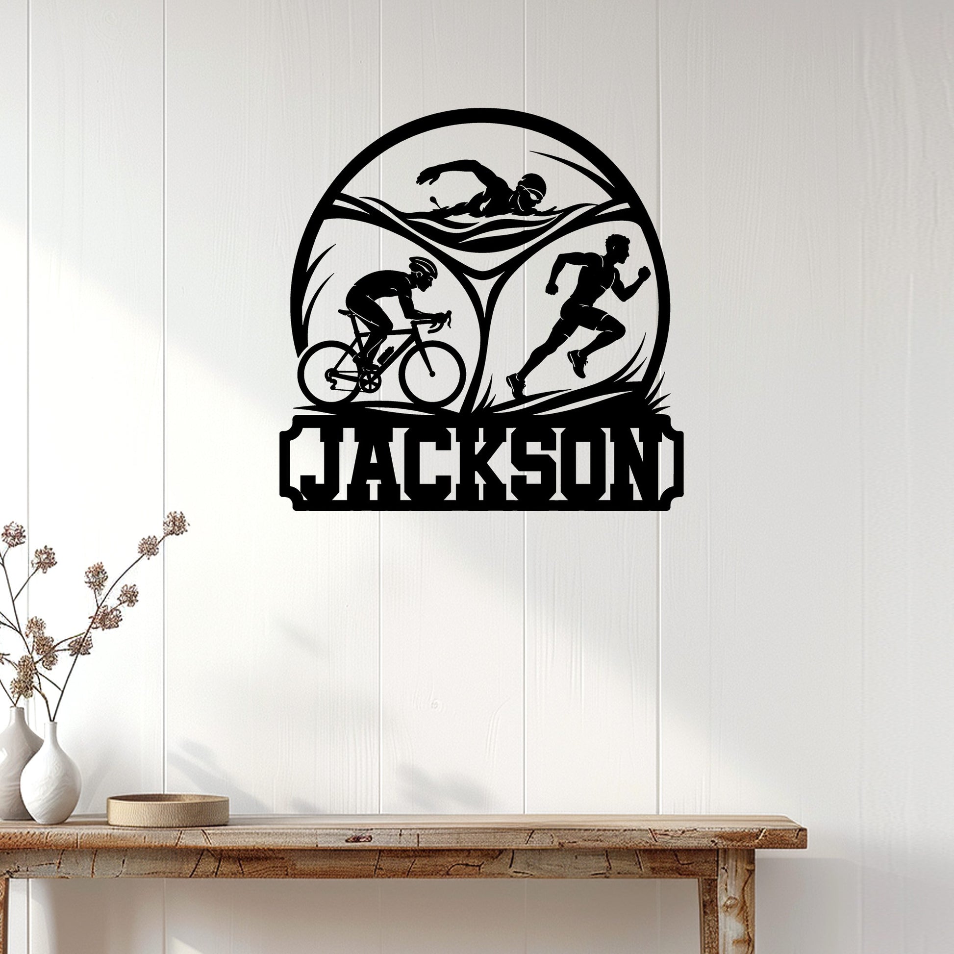 Triathlon wall decor displayed on a white paneled wall, featuring swim, bike, and run silhouettes