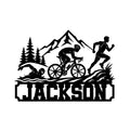 Triathlon metal sign featuring swimmer, cyclist, and runner silhouettes beneath mountain peaks and pine trees