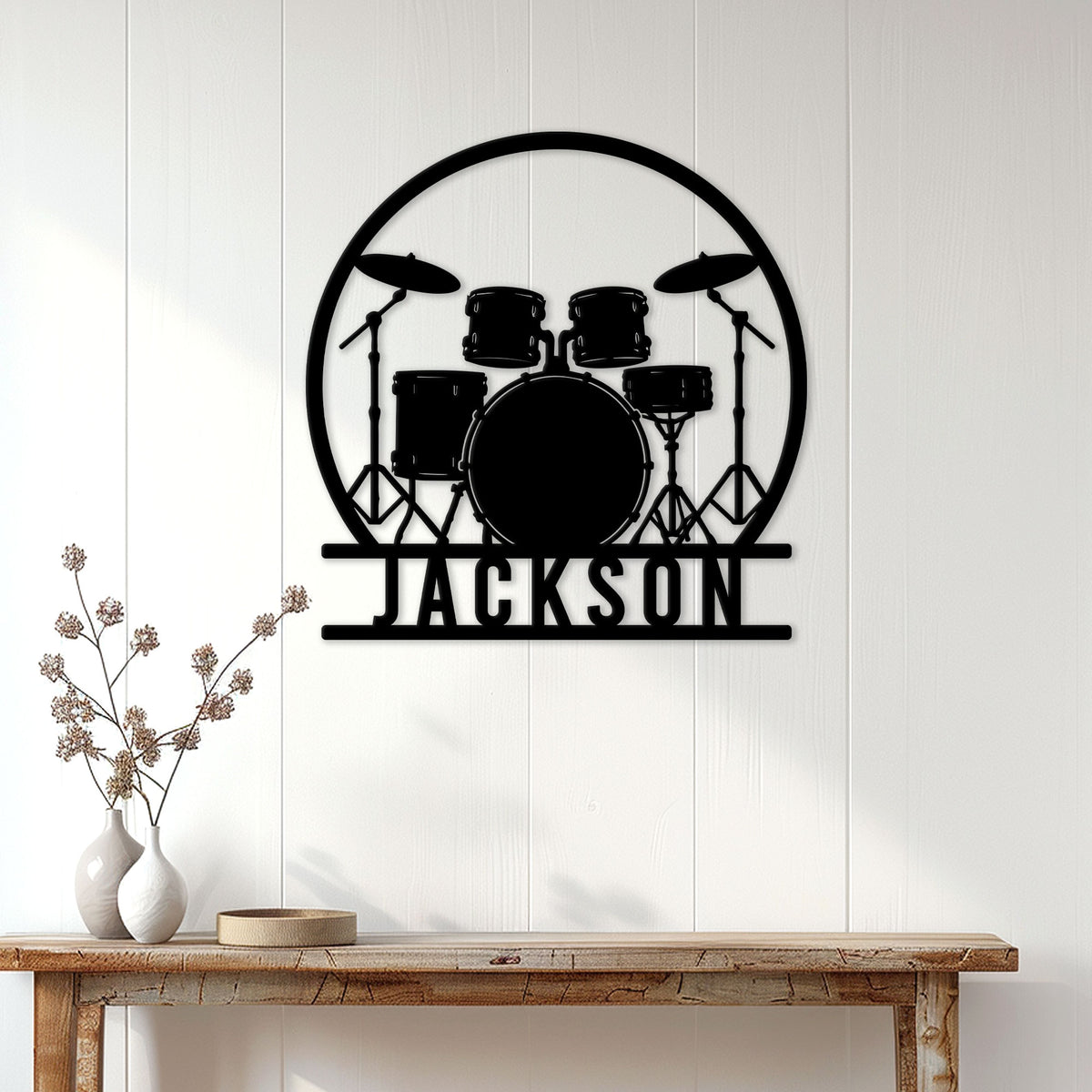 Black drum set metal wall sign displayed above a console table in a bright home interior