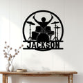 Black drummer metal wall sign displayed on a light paneled wall above a wooden console
