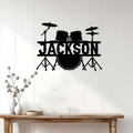 Black drum kit metal wall sign displayed on a white paneled wall above a rustic console table