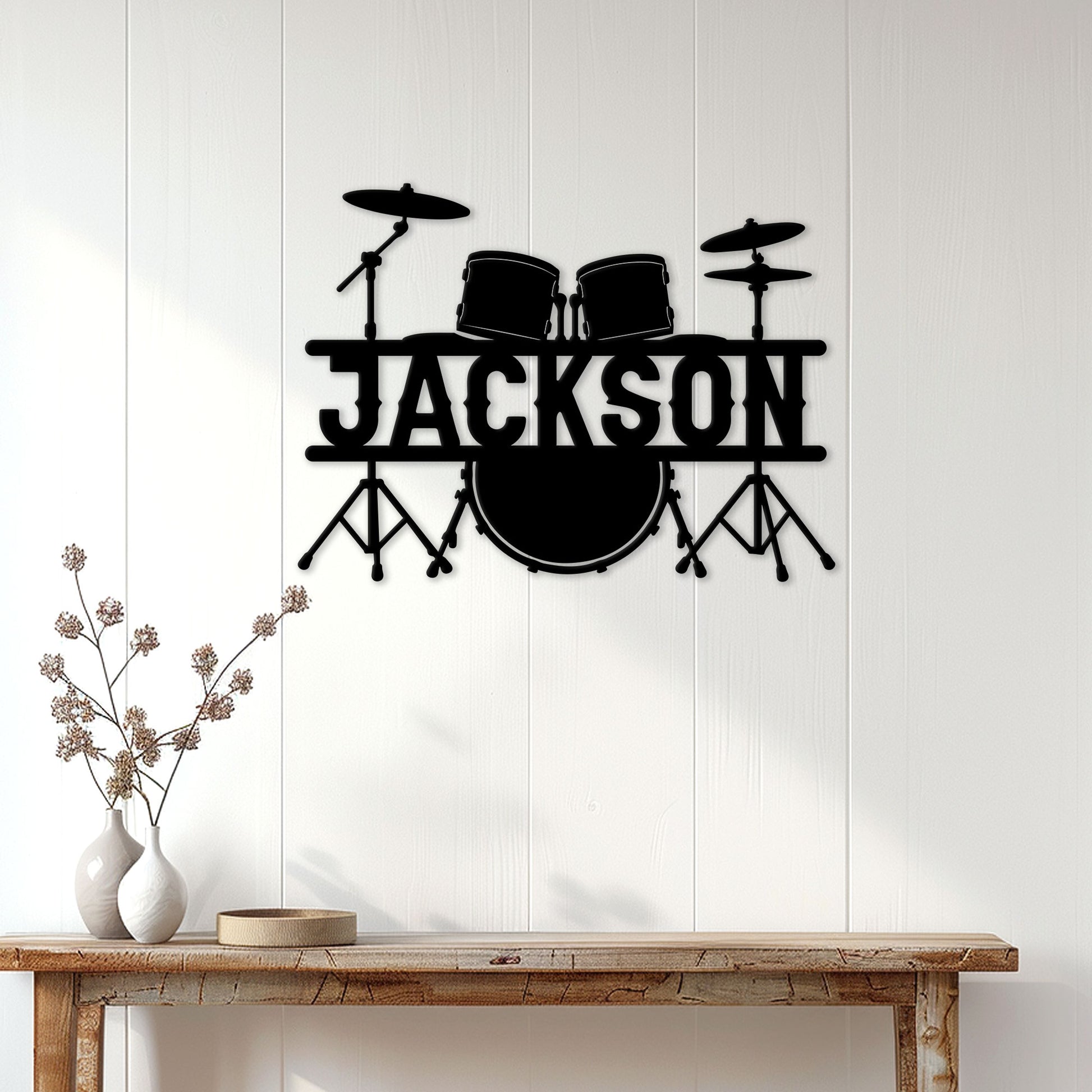 Black drum kit metal wall sign displayed on a white paneled wall above a rustic console table