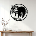 Sloth metal wall sign displayed on a white paneled wall above a rustic console table