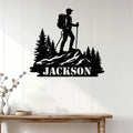 Hiking wall decor displayed on a light wood wall, featuring a backpacker crossing a mountain ridge