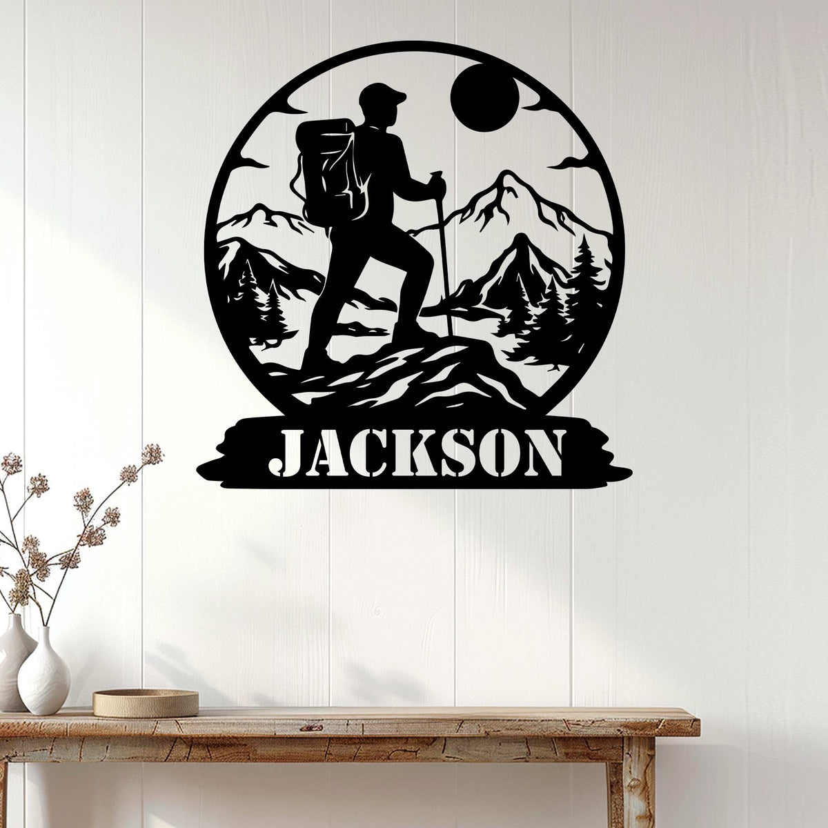 Hiking metal sign displayed on a white wood wall, featuring a mountain trekker and forest landscape