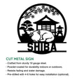Cut metal Shiba Inu sign shown with a sleeping dog, bonsai tree, Japanese building, lantern, and blossom branches
